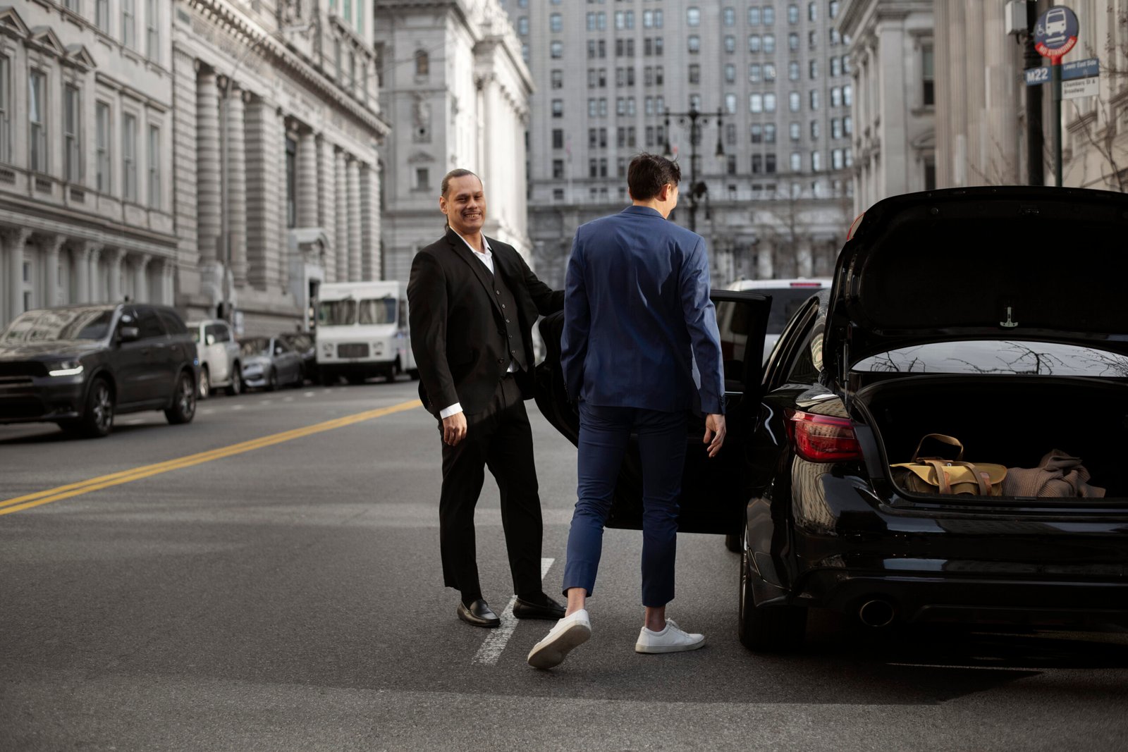 Premium black car driving through city streets at dusk, representing Chauffu's city limo and point-to-point service.